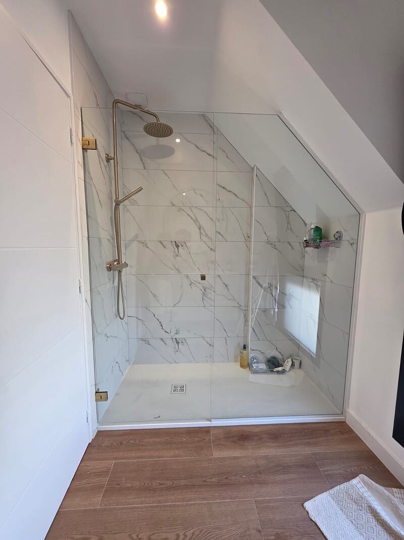 Paroi de douche en verre sur mesure épousant la pente d'un rampant de combles