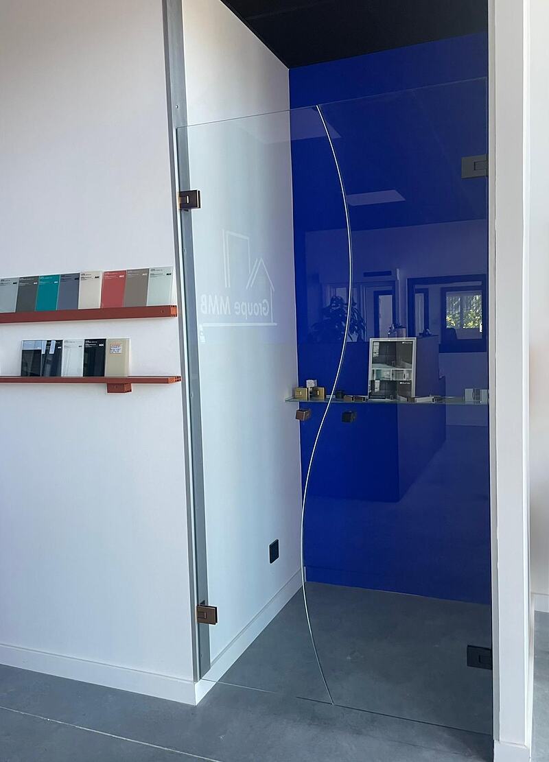 Cloison en verre laqué bleu et porte battante en verre trempé dans le showroom MMB